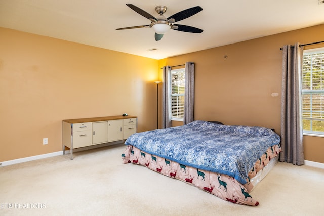 bedroom featuring multiple windows, ceiling fan, and light carpet