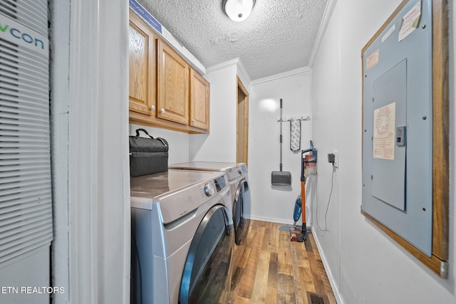 clothes washing area featuring cabinets, light hardwood / wood-style flooring, independent washer and dryer, electric panel, and ornamental molding