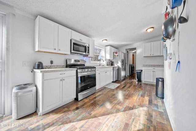 kitchen featuring appliances with stainless steel finishes, a textured ceiling, dark wood-type flooring, sink, and white cabinets