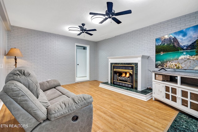 living room with ceiling fan, hardwood / wood-style floors, and brick wall