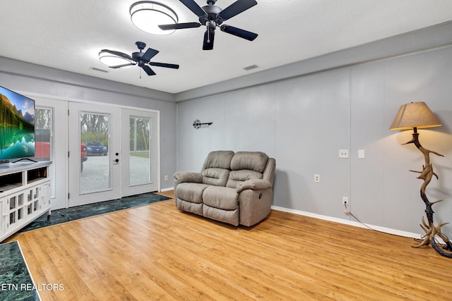 sitting room with ceiling fan, wood-type flooring, a textured ceiling, and french doors