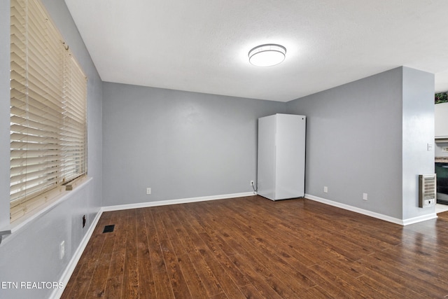 unfurnished room with dark hardwood / wood-style flooring and a textured ceiling