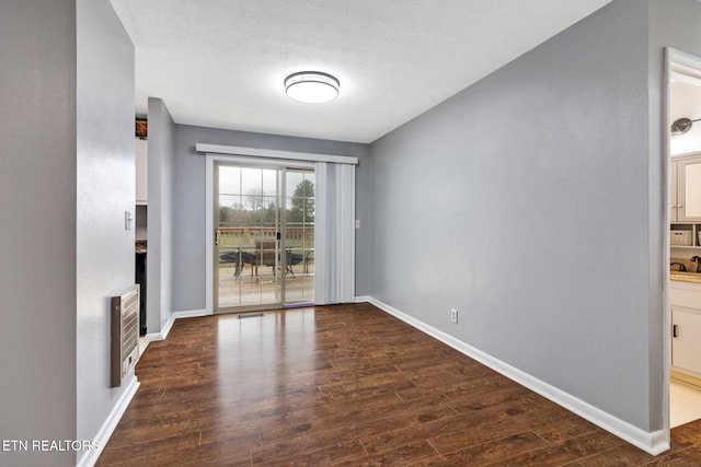 unfurnished dining area featuring heating unit, dark wood-type flooring, and a textured ceiling