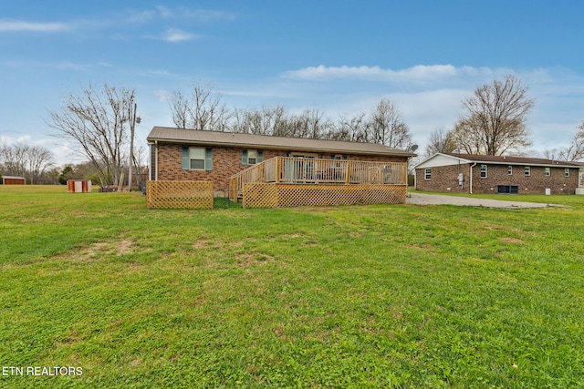 ranch-style house with a wooden deck, a front lawn, and a storage shed