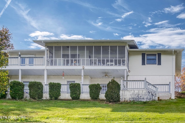 rear view of property with a lawn and a sunroom