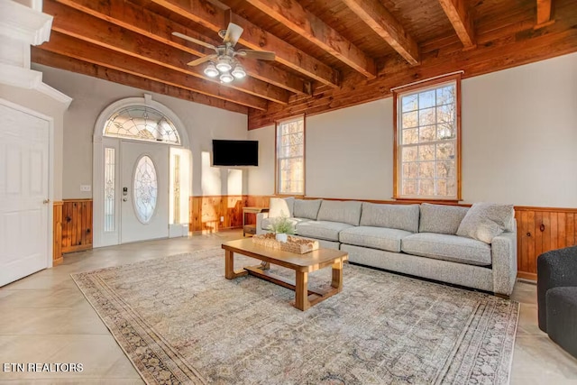 living room with beam ceiling, wood walls, ceiling fan, and wood ceiling