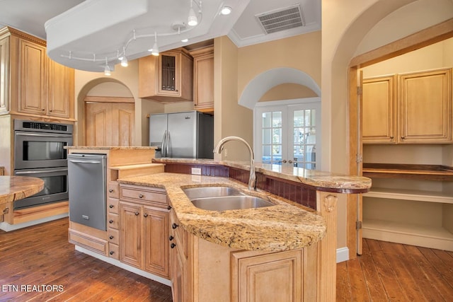 kitchen featuring sink, ornamental molding, dark hardwood / wood-style floors, a center island with sink, and appliances with stainless steel finishes