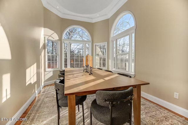 dining space with a high ceiling, light wood-type flooring, plenty of natural light, and ornamental molding