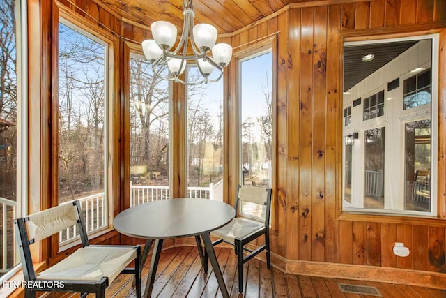 interior space featuring wood walls, a healthy amount of sunlight, hardwood / wood-style floors, and an inviting chandelier