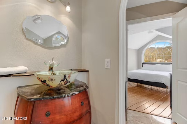 bathroom with tile patterned floors, vanity, and vaulted ceiling