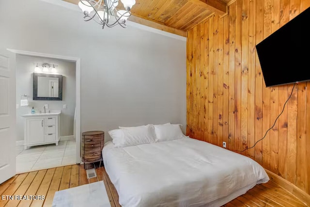 bedroom with connected bathroom, an inviting chandelier, wooden ceiling, and hardwood / wood-style flooring