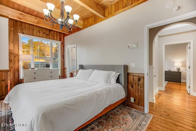 bedroom with wood walls, an inviting chandelier, light wood-type flooring, and wooden ceiling