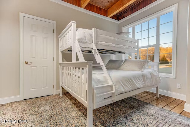 bedroom featuring beamed ceiling, hardwood / wood-style flooring, and wooden ceiling