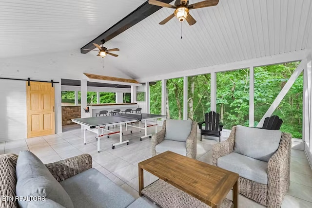 interior space with lofted ceiling with beams, a healthy amount of sunlight, a barn door, and ceiling fan