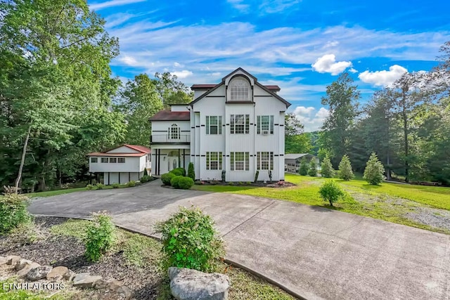 view of front of house with a front yard and a balcony