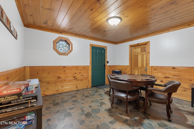 dining space featuring wood walls, ornamental molding, and wood ceiling