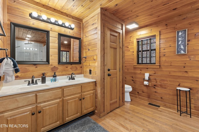 bathroom with vanity, wooden walls, wooden ceiling, hardwood / wood-style floors, and toilet