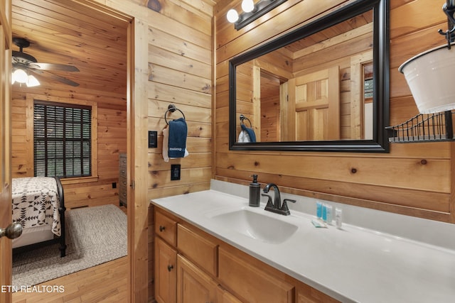 bathroom featuring vanity, hardwood / wood-style flooring, ceiling fan, and wood walls