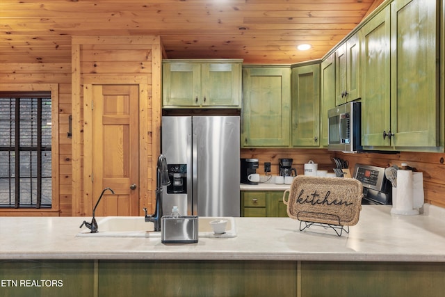 kitchen featuring green cabinets, wood ceiling, stainless steel appliances, and wooden walls