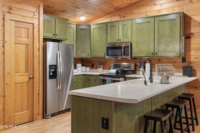 kitchen featuring stainless steel appliances, green cabinetry, lofted ceiling, and sink