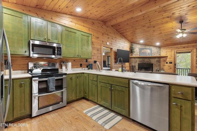 kitchen featuring light wood-type flooring, stainless steel appliances, sink, green cabinetry, and lofted ceiling