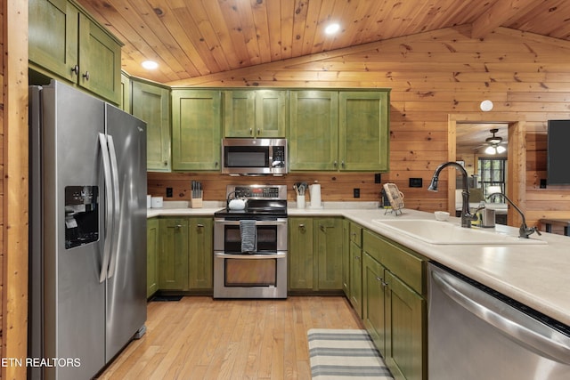 kitchen with light wood-type flooring, stainless steel appliances, sink, lofted ceiling with beams, and green cabinetry