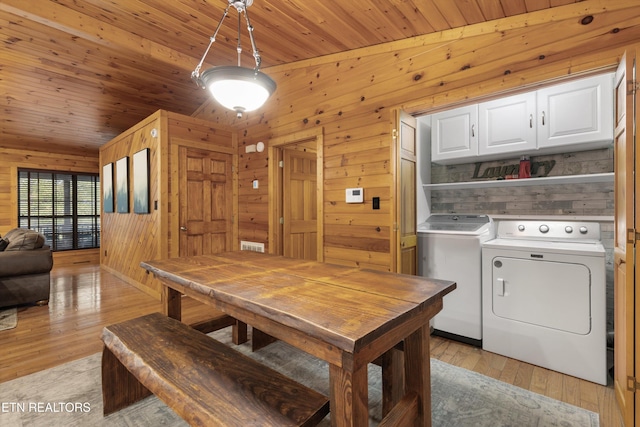 dining space featuring washing machine and dryer, light hardwood / wood-style flooring, wooden ceiling, and wood walls