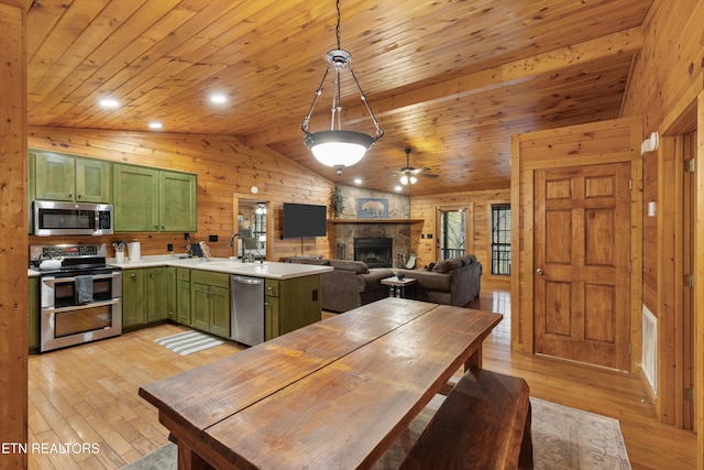 kitchen featuring sink, stainless steel appliances, green cabinets, decorative light fixtures, and light wood-type flooring