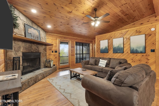 living room featuring wood walls, wooden ceiling, vaulted ceiling, light hardwood / wood-style flooring, and a fireplace