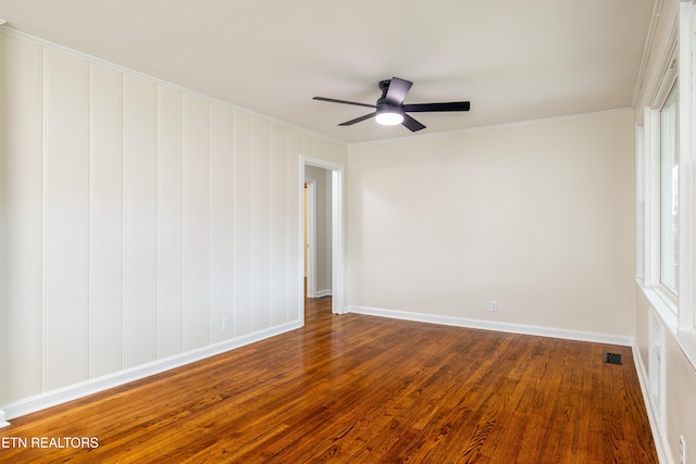 empty room with visible vents, crown molding, baseboards, dark wood-type flooring, and a ceiling fan