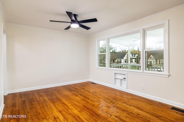 unfurnished room with visible vents, wood finished floors, baseboards, and ornamental molding