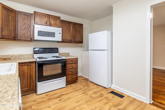 kitchen with visible vents, light wood-style flooring, white appliances, and crown molding