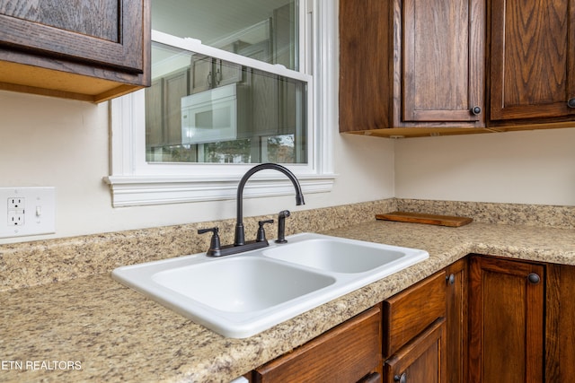 kitchen with light countertops, dark brown cabinetry, and a sink