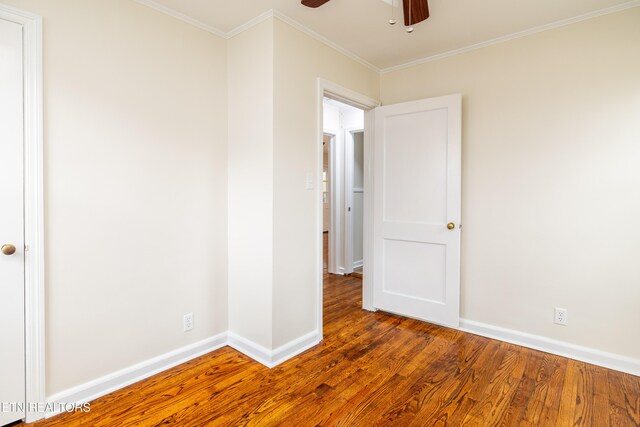 spare room featuring a ceiling fan, wood finished floors, baseboards, and ornamental molding