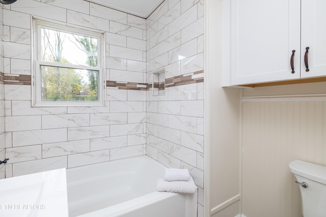 bathroom featuring tiled shower / bath combo and toilet