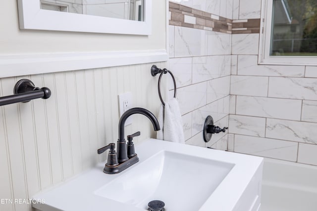 interior details featuring a sink, a wainscoted wall, and walk in shower