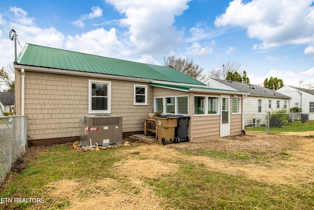 back of house featuring central air condition unit, metal roof, and fence