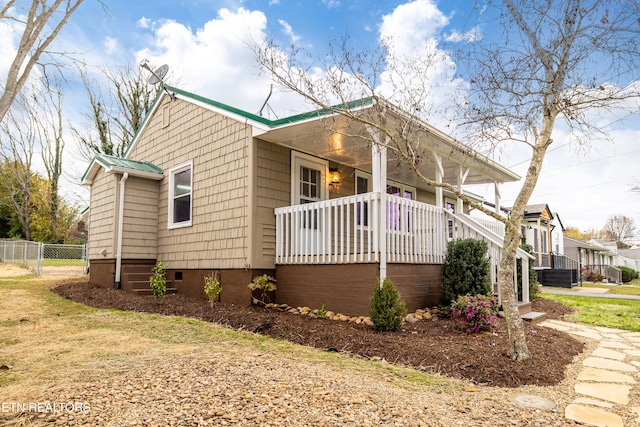 view of side of home with fence, covered porch, and metal roof