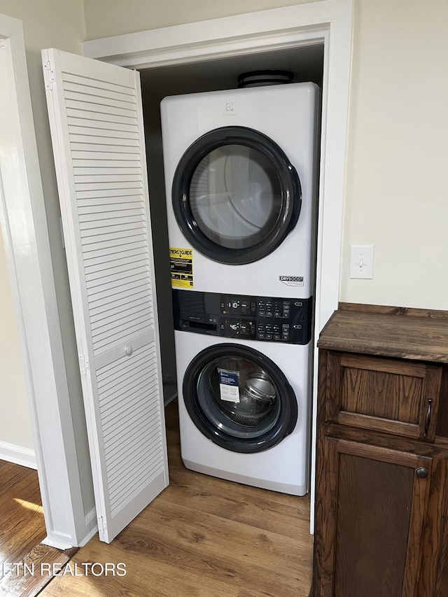 laundry room featuring stacked washer / dryer, laundry area, and wood finished floors