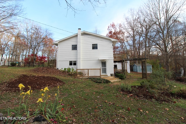 back of house with a storage unit, a yard, and a wooden deck