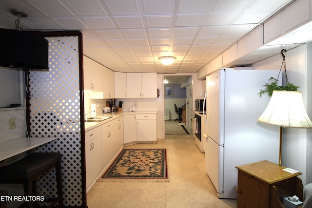 kitchen with white cabinetry, sink, light tile patterned floors, and white appliances