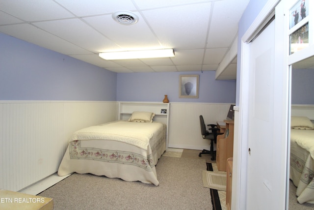 bedroom with a drop ceiling and light carpet