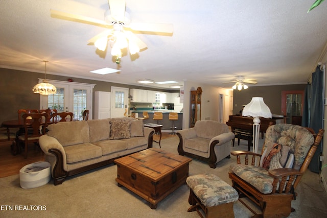 carpeted living room featuring french doors, ceiling fan, and ornamental molding