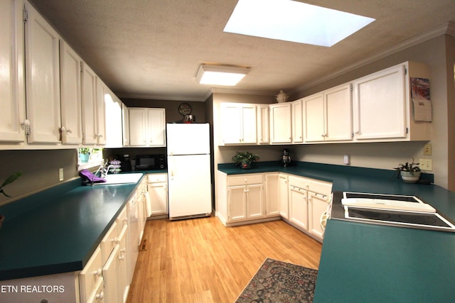 kitchen with white fridge, white cabinetry, a skylight, and crown molding