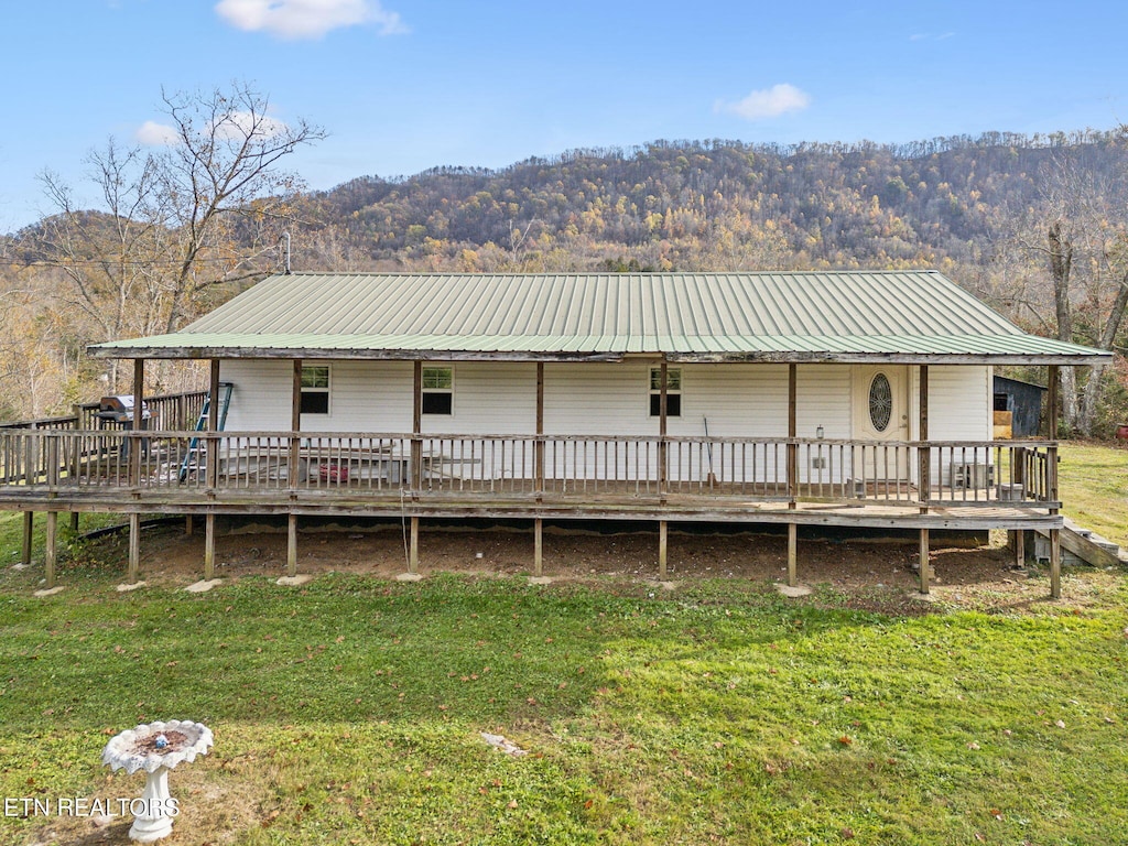 rear view of property featuring a yard and a deck with mountain view