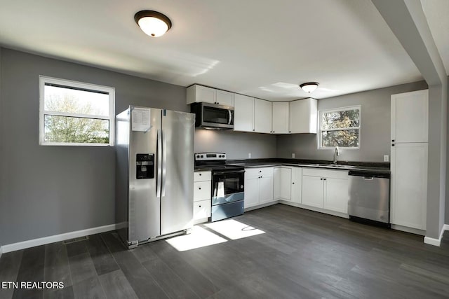 kitchen with white cabinets, appliances with stainless steel finishes, dark hardwood / wood-style floors, and a healthy amount of sunlight