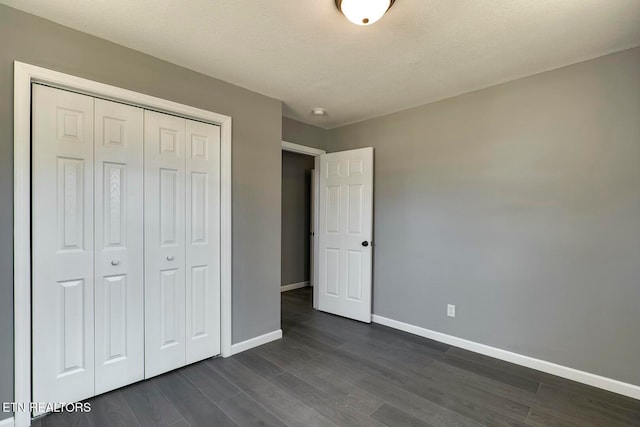 unfurnished bedroom with a textured ceiling, a closet, and dark hardwood / wood-style floors