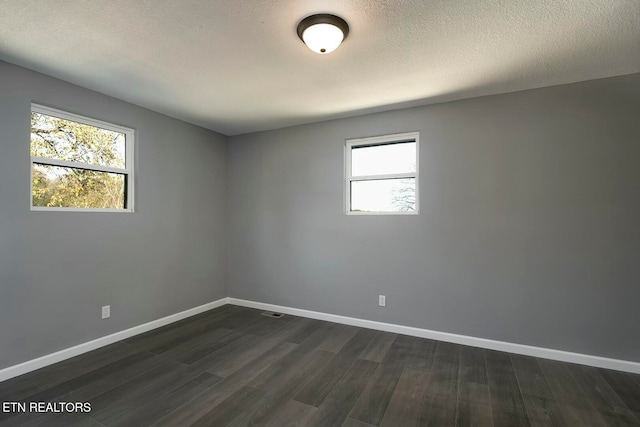 unfurnished room with a textured ceiling and dark hardwood / wood-style floors