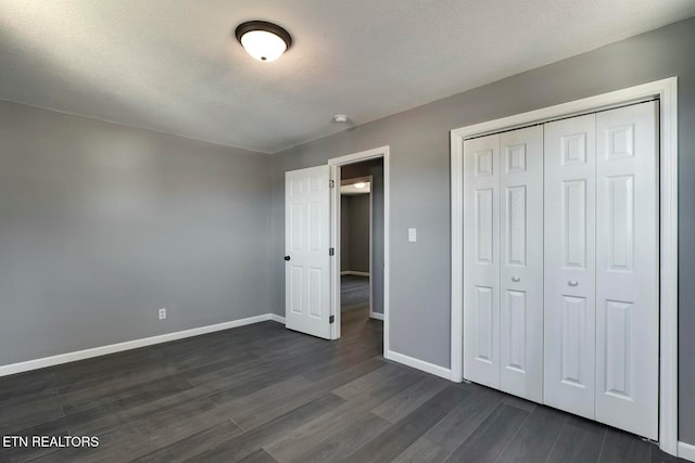 unfurnished bedroom with a textured ceiling, dark hardwood / wood-style floors, and a closet