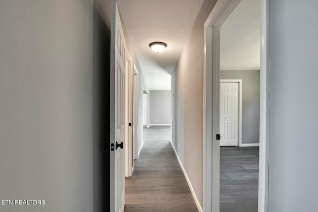 hall with dark hardwood / wood-style flooring and a textured ceiling